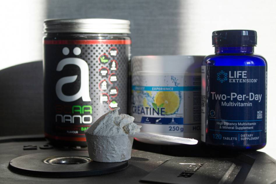A hand holding a digestive enzyme capsule next to a journal and fresh vegetables